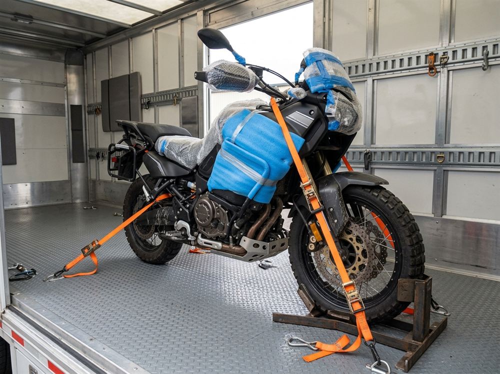 Adventure motorcycle secured with heavy-duty ratchets and protective foam in clean transport vehicle